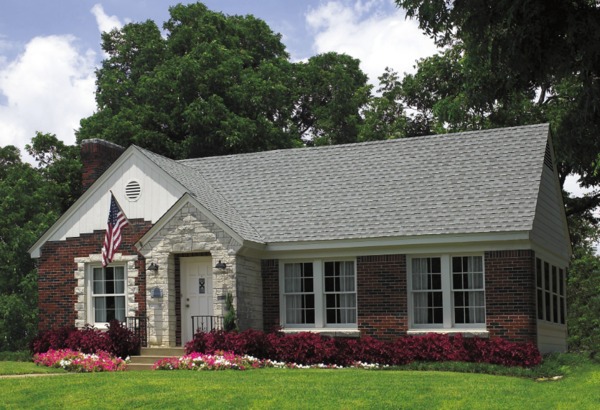 Brick front home with shingle roof and white gutters.